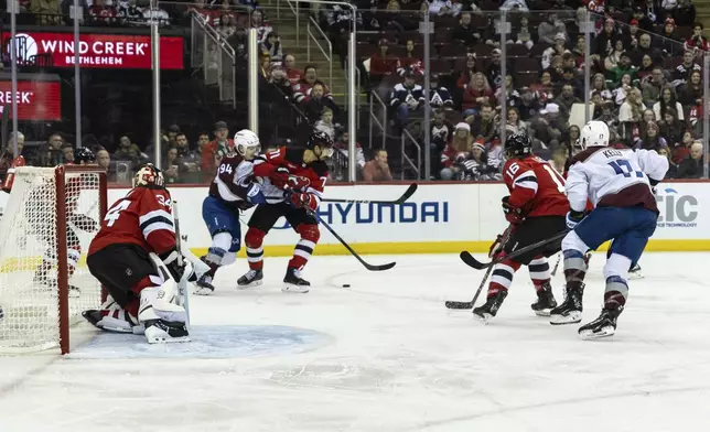 New Jersey Devils defenseman Jonas Siegenthaler and Colorado Avalanche left wing Joel Kiviranta (94) tussle for the puck during the first period of an NHL hockey game, Sunday, Dec. 8, 2024, in Newark, N.J. (AP Photo/Stefan Jeremiah)