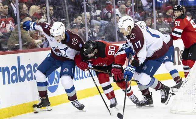 Colorado Avalanche defenseman Cale Makar (8) and center Parker Kelly (17) tussle with New Jersey Devils left wing Tomas Tatar (90) for the puck during the second period of an NHL hockey game, Sunday, Dec. 8, 2024, in Newark, N.J. (AP Photo/Stefan Jeremiah)