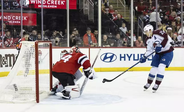 New Jersey Devils goaltender Jake Allen saves a shot from Colorado Avalanche center Nathan MacKinnon during the first period of an NHL hockey game, Sunday, Dec. 8, 2024, in Newark, N.J. (AP Photo/Stefan Jeremiah)