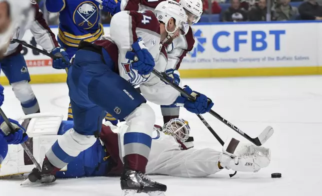 Colorado Avalanche goalie Scott Wedgewood, bottom, reaches for a loose puck with defenseman Calvin de Haan, left, and right wing Nikolai Kovalenko, back, during the second period of an NHL hockey game against the Buffalo Sabres in Buffalo, N.Y., Tuesday, Dec. 3, 2024. (AP Photo/Adrian Kraus)