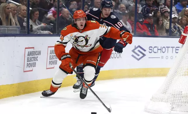 Anaheim Ducks defenseman Pavel Mintyukov (34) controls the puck as Columbus Blue Jackets left wing Dmitri Voronkov (10) defends during the second period of an NHL hockey game Saturday, Dec. 14, 2024, in Columbus, Ohio. (AP Photo/Joe Maiorana)