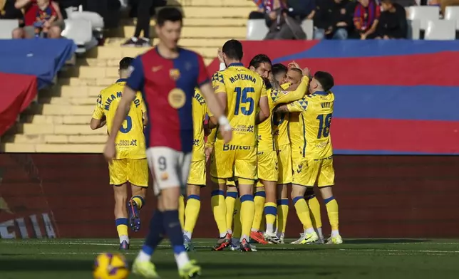 Las Palmas' players celebrate after their teammate Sandro Ramirez scoring the opening goal against Barcelona during a Spanish La Liga soccer match at the Lluis Companys Olympic Stadium in Barcelona, Spain, Saturday Nov. 30, 2024. (AP Photo/Joan Monfort)