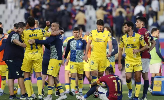 Las Palmas' players celebrate their team's 2-1 victory over Barcelona at the end of a Spanish La Liga soccer match at the Lluis Companys Olympic Stadium in Barcelona, Spain, Saturday Nov. 30, 2024. (AP Photo/Joan Monfort)