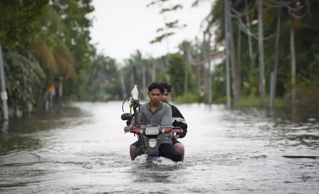 Residents ride on a self modified motorcycle through a road covered by flood water in Tumpat, outskirts of Kota Bahru, Malaysia, Tuesday, Dec. 3, 2024. (AP Photo/Vincent Thian)