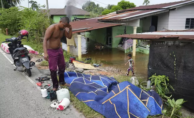 A man dries items he removed from his flooded house in Tumpat, on the outskirts of Kota Bahru in Kelantan state on the east coast of Malaysia, Tuesday, Dec. 3, 2024. (AP Photo/Vincent Thian)