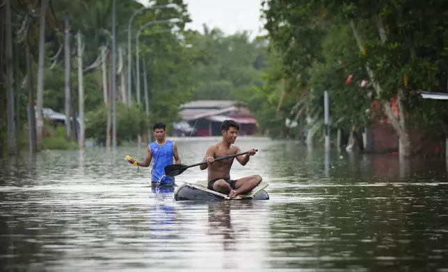 Children wade through flood waters in Tumpat, outskirts of Kota Bahru, Malaysia, Tuesday, Dec. 3, 2024. (AP Photo/Vincent Thian)