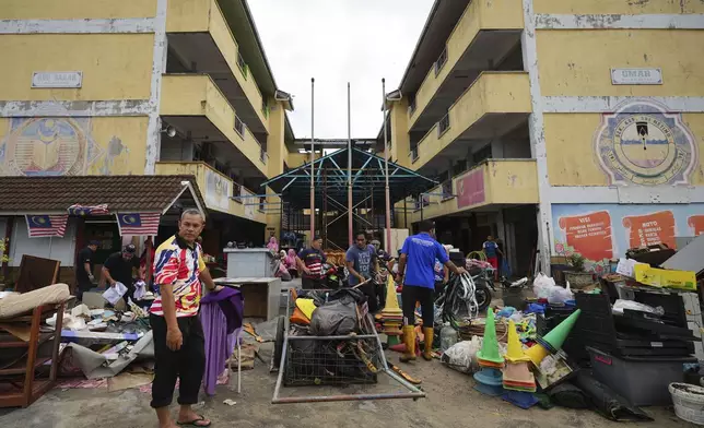 People remove items from a flooded school in Tumpat, on the outskirts of Kota Bahru, Malaysia, Tuesday, Dec. 3, 2024. (AP Photo/Vincent Thian)