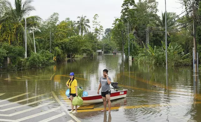 People use a boat to cross a flooded area in Tumpat, outskirts of Kota Bahru in Kelantan state on the east coast of Malaysia, Tuesday, Dec. 3, 2024. (AP Photo/Vincent Thian)