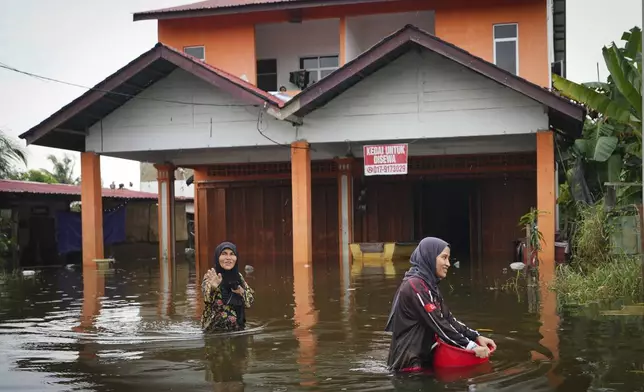 Residents wade through flood water outside their home in Tumpat, outskirts of Kota Bahru, Malaysia, Tuesday, Dec. 3, 2024. (AP Photo/Vincent Thian)