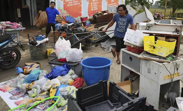 Men remove items from a school affected by a flood in Tumpat, on the outskirts of Kota Bahru, Malaysia, Tuesday, Dec. 3, 2024. (AP Photo/Vincent Thian)