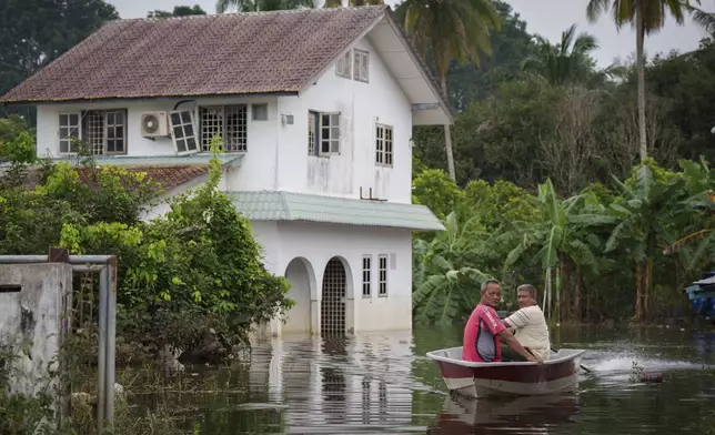 People use a boat to cross a flooded area in Tumpat, Tumpat, outskirts of Kota Bahru, Malaysia, Tuesday, Dec. 3, 2024. (AP Photo/Vincent Thian)