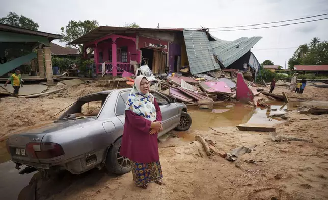 Asmah Ibrahim, 60 years old resident reacts as she stands outside of her house damaged by flood in Tumpat, on the outskirts of Kota Bahru, Malaysia, Tuesday, Dec. 3, 2024. (AP Photo/Vincent Thian)