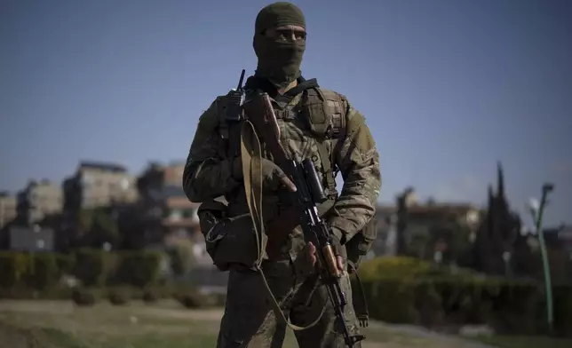 A member of the new armed forces, former rebel who took part in the overthrow of Bashar Assad's government and now serves in the new Syrian government, poses for a picture as he stands at a square before a military parade in Damascus, Syria, Friday, Dec. 27, 2024. (AP Photo/Leo Correa)