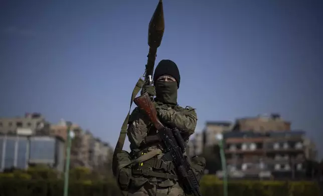 A member of the new armed forces, former rebel who took part in the overthrow of Bashar Assad's government and now serves in the new Syrian government, poses for a picture as he stands at a square before a military parade in Damascus, Syria, Friday, Dec. 27, 2024. (AP Photo/Leo Correa)