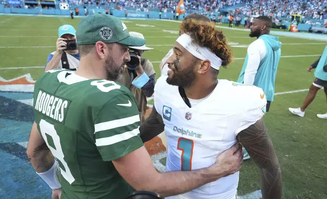 Miami Dolphins quarterback Tua Tagovailoa (1) and New York Jets quarterback Aaron Rodgers (8) talk at the end of an NFL football game, Sunday, Dec. 8, 2024, in Miami Gardens, Fla. (AP Photo/Wilfredo Lee)