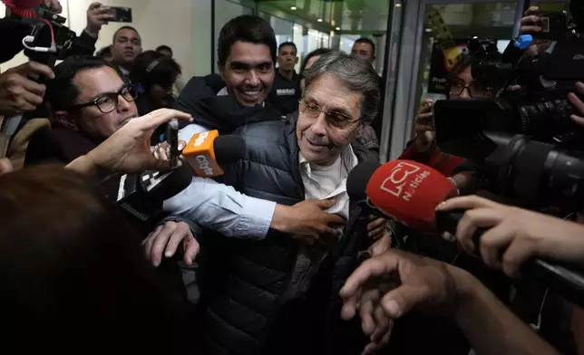 Media swarm Fabio Ochoa, center, a former member of Cartel of Medellin, upon his arrival at El Dorado airport, after being deported from the United States, in Bogota, Colombia, Monday, Dec. 23, 2024. (AP Photo/Fernando Vergara)