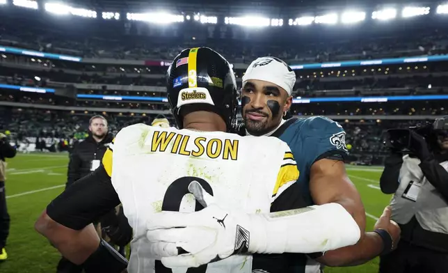 Philadelphia Eagles quarterback Jalen Hurts and Pittsburgh Steelers quarterback Russell Wilson embrace after an NFL football game Sunday, Dec. 15, 2024, in Philadelphia. (AP Photo/Derik Hamilton)