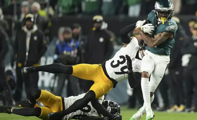 Philadelphia Eagles wide receiver DeVonta Smith (6) is tackled after a catch by Pittsburgh Steelers safety Minkah Fitzpatrick (39) and Steelers' Cameron Sutton during the second half of an NFL football game Sunday, Dec. 15, 2024, in Philadelphia. (AP Photo/Matt Slocum)