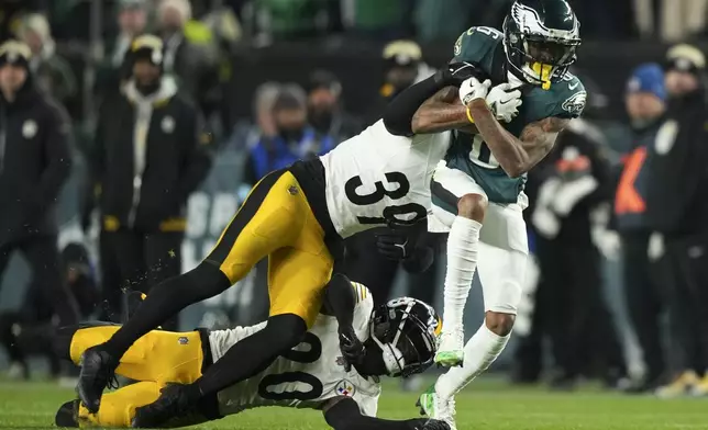 Philadelphia Eagles wide receiver DeVonta Smith (6) is tackled after a catch by Pittsburgh Steelers safety Minkah Fitzpatrick (39) and Steelers' Cameron Sutton (20) during the second half of an NFL football game Sunday, Dec. 15, 2024, in Philadelphia. (AP Photo/Matt Slocum)