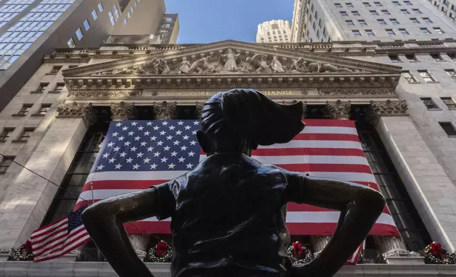 The New York Stock Exchange is shown behind the statue titled "Fearless Girl", Thursday, Dec. 12, 2024, in New York. (AP Photo/Julia Demaree Nikhinson)