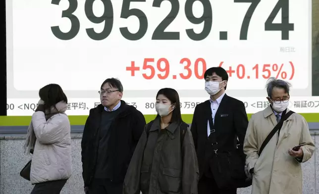 People stand in front of an electronic stock board showing Japan's Nikkei index at a securities firm Monday, Dec. 16, 2024, in Tokyo. (AP Photo/Eugene Hoshiko)