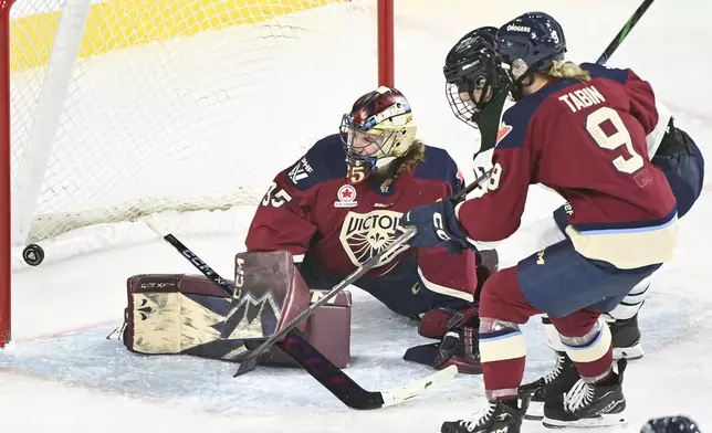 Montreal Victoire goaltender Ann-Renee Desbiens, left, is scored against by Boston Fleet's Hilary Knight, back right, as Victoire's Kati Tabin (9) defends during second-period PWHL hockey game action in Laval, Quebec, Monday, Dec. 30, 2024. (Graham Hughes/The Canadian Press via AP)