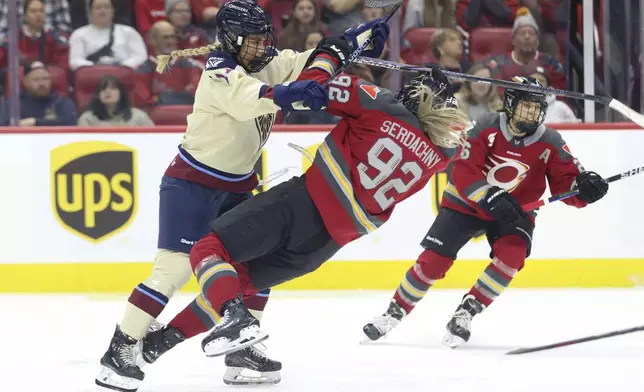 Montreal Victoire's Dara Greig, left, checks Ottawa Charge's Danielle Serdachny (92) during second-period PWHL hockey game action in Ottawa, Ontario, Friday, Dec. 6, 2024. (Patrick Doyle/The Canadian Press via AP)