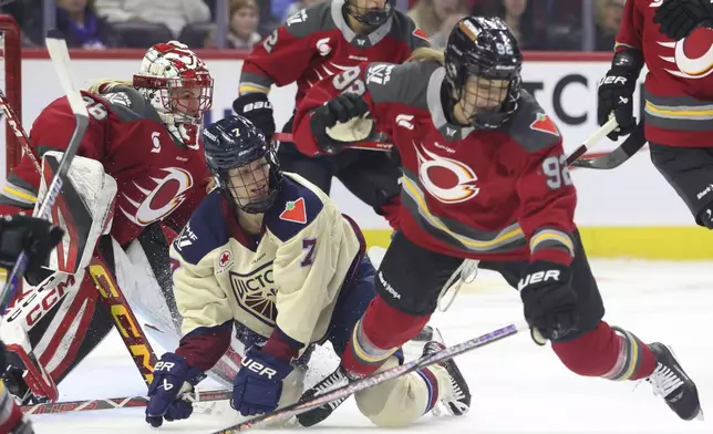 Montreal Victoire's Laura Stacey (7) and Ottawa Charge's Danielle Serdachny (92) fall as Charge goaltender Emerance Maschmeyer (38) looks on during first-period PWHL hockey game action in Ottawa, Ontario, Friday, Dec. 6, 2024. (Patrick Doyle/The Canadian Press via AP)