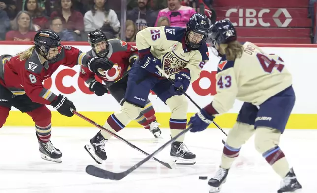 Montreal Victoire's Lina Ljungblom (25) passes the puck to Kristin O'Neill (43) as Ottawa Charge's Natalie Snodgrass (8) defends during the third period of a PWHL hockey game in Ottawa, Ontario on Friday, Dec. 6, 2024. (Patrick Doyle/The Canadian Press via AP)