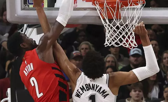 Portland Trail Blazers center Deandre Ayton (2) dunks the ball on San Antonio Spurs center Victor Wembanyama (1) during the first half of an NBA basketball game in San Antonio, Saturday, Dec. 21, 2024. (AP Photo/Kin Man Hui)