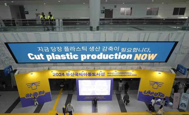 People pass under an electric display board calling for a reduction in plastic production near the venue for the fifth session of the Intergovernmental Negotiating Committee on Plastic Pollution in Busan, South Korea, Sunday, Dec. 1, 2024. (AP Photo/Ahn Young-joon)