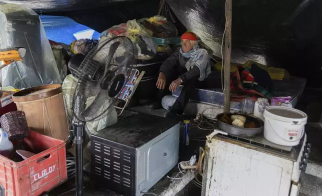 Amilcar Veron sits in a makeshift tent on the roof of his house with the belongings he saved from floods in Durazno, Uruguay, May 13, 2024. (AP Photo/Matilde Campodonico)