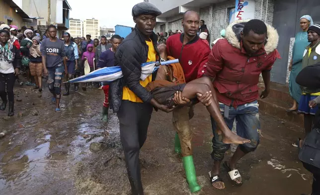 Residents rescue a woman who was caught amid the rain in the Mathare slum of Nairobi, Kenya, April 24, 2024. (AP Photo/Andrew Kasuku)