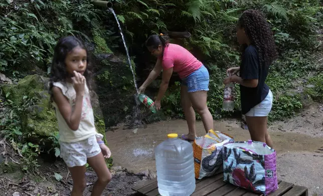 Residents collect drinking water that falls naturally down a mountain in the Rocinha favela of Rio de Janeiro, Brazil, March 18, 2024. (AP Photo/Silvia Izquierdo)