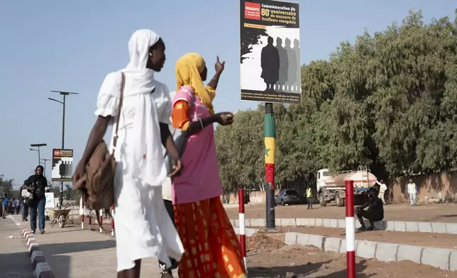 A student points at a poster marking the 80th anniversary of the Thiaroye massacre in Thiaroye, Senegal, Thursday, Nov. 28, 2024. (AP Photo/Sylvain Cherkaoui)