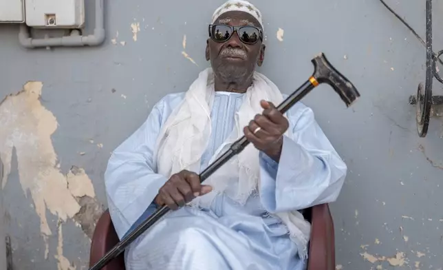 Biram Senghor, whose father Mbap was killed in 1944, poses at the entrance to his brother Amhet's house, in Rufisque, Senegal, Thursday, Nov. 28, 2024. (AP Photo/Sylvain Cherkaoui)