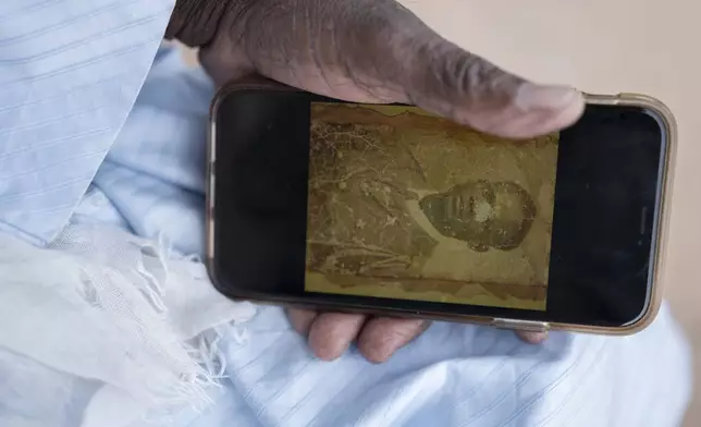 Biram Senghor, whose father was killed in 1944, holds a phone with a photo of his father, in Rufisque, Senegal, Thursday, Nov. 28, 2024. (AP Photo/Sylvain Cherkaoui)