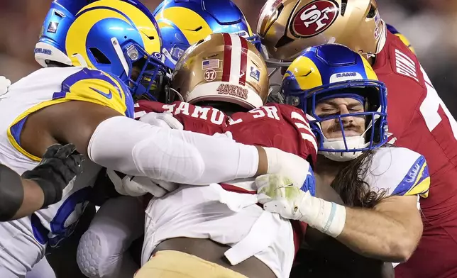 San Francisco 49ers wide receiver Deebo Samuel Sr., center, is tackled by Los Angeles Rams linebacker Christian Rozeboom, front right, and others during the first half of an NFL football game in Santa Clara, Calif., Thursday, Dec. 12, 2024. (AP Photo/Godofredo A. Vásquez)