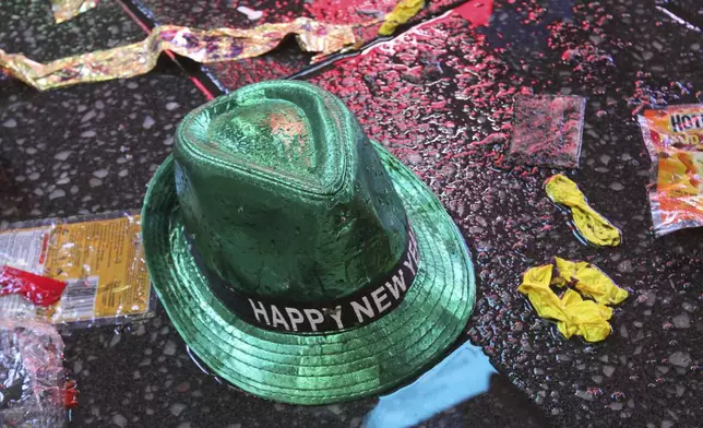 FILE - In this Jan. 1, 2019, file photo a "Happy New Year" hat lies on the wet ground along with other items following the celebration in New York's Times Square. (AP Photo/Tina Fineberg, File)