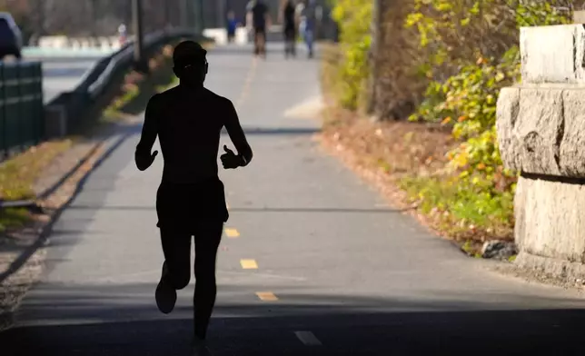 FILE - A runner appears in silhouette while running in temperatures in the 70s, Wednesday, Nov. 6, 2024, under a bridge near the Charles River, in Boston. (AP Photo/Steven Senne, File)