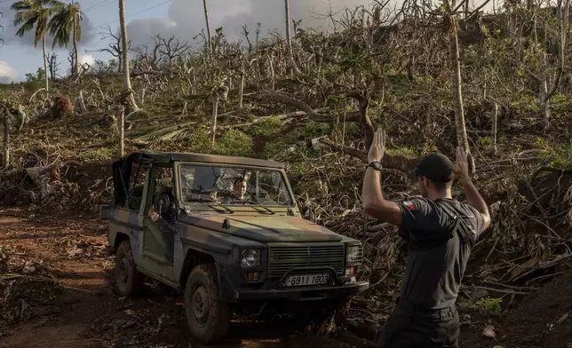 French civil security officers make their way through shredded trees heading to Mirereni, Mayotte, Friday, Dec. 20, 2024. (AP Photo/Adrienne Surprenant)