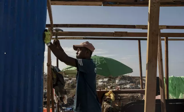Djoche Ahmed, 18, and his father Ahmed Attoumane, 47, repair their family house in Majicavo Koropa, Mayotte, Friday, Dec. 20, 2024. (AP Photo/Adrienne Surprenant)