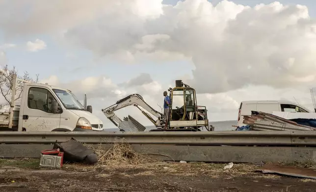 Construction crew clear debris from the area near Longoni port, Mayotte, Friday, Dec. 20, 2024. (AP Photo/Adrienne Surprenant)