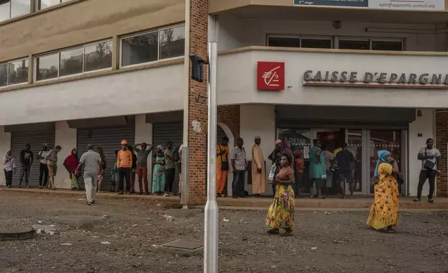 People wait in line to get cash, in Mamoudzou, Mayotte, Friday, Dec. 20, 2024. (AP Photo/Adrienne Surprenant)