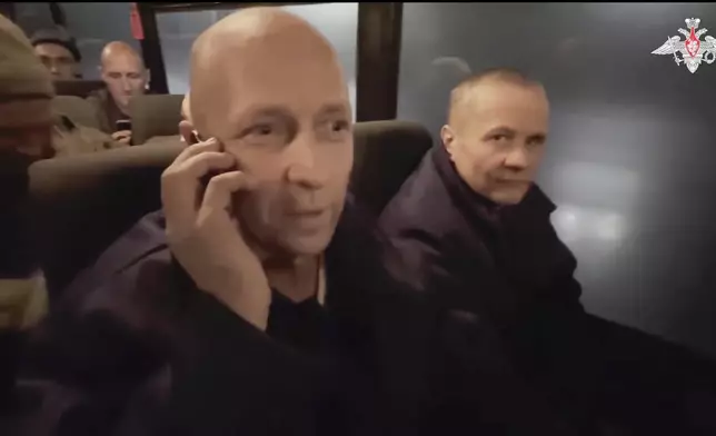 In this photo taken from video released by the Russian Defense Ministry Press Service on Monday, Dec. 30, 2024, a Russian soldier speaks on the phone with his relatives as he and others sit in a bus after being released in a prisoners swap between Russia and Ukraine, at an unspecified location in Belarus. (Russian Defense Ministry Press Service via AP)