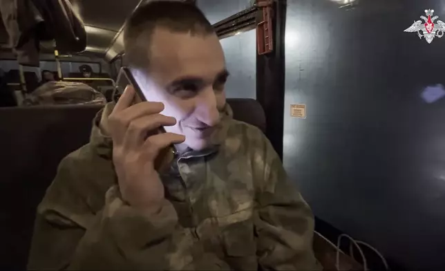 In this photo taken from video released by the Russian Defense Ministry Press Service on Monday, Dec. 30, 2024, a Russian soldier speaks on the phone with his relatives as he and others sit in a bus after being released in a prisoners swap between Russia and Ukraine, at an unspecified location in Belarus. (Russian Defense Ministry Press Service via AP)