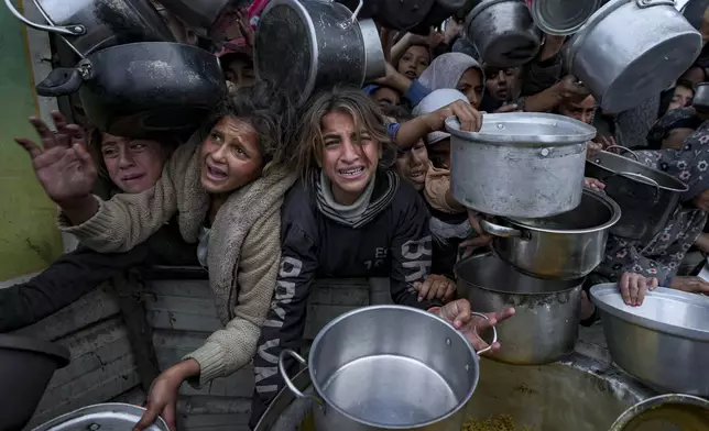 Palestinian women and girls struggle to reach for food at a distribution center in Khan Younis, Gaza Strip, Friday, Dec. 20, 2024. (AP Photo/Abdel Kareem Hana)