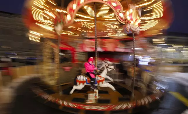 A girl rides a carousel at a Christmas fair opened prior to incoming Christmas and New Year festivities in St. Petersburg, Russia, Friday, Dec. 20, 2024. (AP Photo/Dmitri Lovetsky)