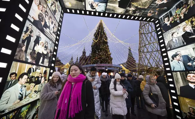 People walk along a Christmas Market set up in Manezhnaya Square decorated for the New Year and Christmas festivities, with the Historical Museum and the Kremlin in the background in Moscow, Russia, Friday, Dec. 20, 2024. (AP Photo/Alexander Zemlianichenko)