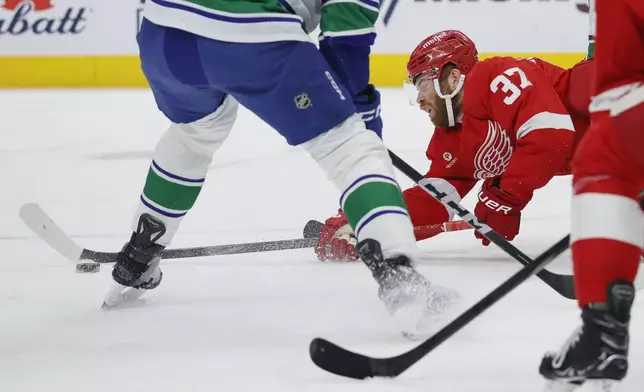 Detroit Red Wings left wing J.T. Compher (37) tries to get a shot off as he falls to the ice against the Vancouver Canucks during the first period of an NHL hockey game Sunday, Dec. 1, 2024, in Detroit. (AP Photo/Duane Burleson)